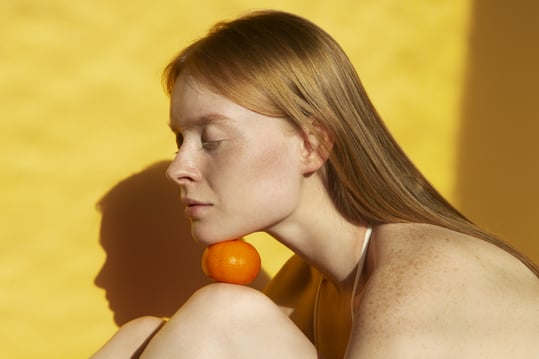 medium-shot-young-woman-posing-with-tangerine