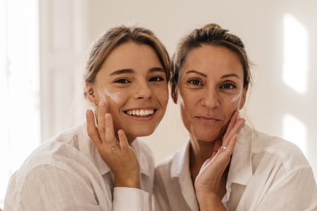 primer-plano-dos-lindas-mujeres-caucasicas-untando-su-cara-crema-mirando-camara-sobre-fondo-blanco-concepto-belleza-juventud